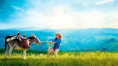 Antoinette (Laure Calamy) zieht auf einer Wiese am Führstrick eines bepackten Esels. Im Hintergrund liegen bewaldete Berge. - Foto: © SWR/Chapka Films/La Filmerie/France 3 Cinema/Julien Panié Antoinette (Laure Calamy) zieht auf einer Wiese am Führstrick eines bepackten Esels. Im Hintergrund liegen bewaldete Berge. - Foto: © SWR/Chapka Films/La Filmerie/France 3 Cinema/Julien Panié