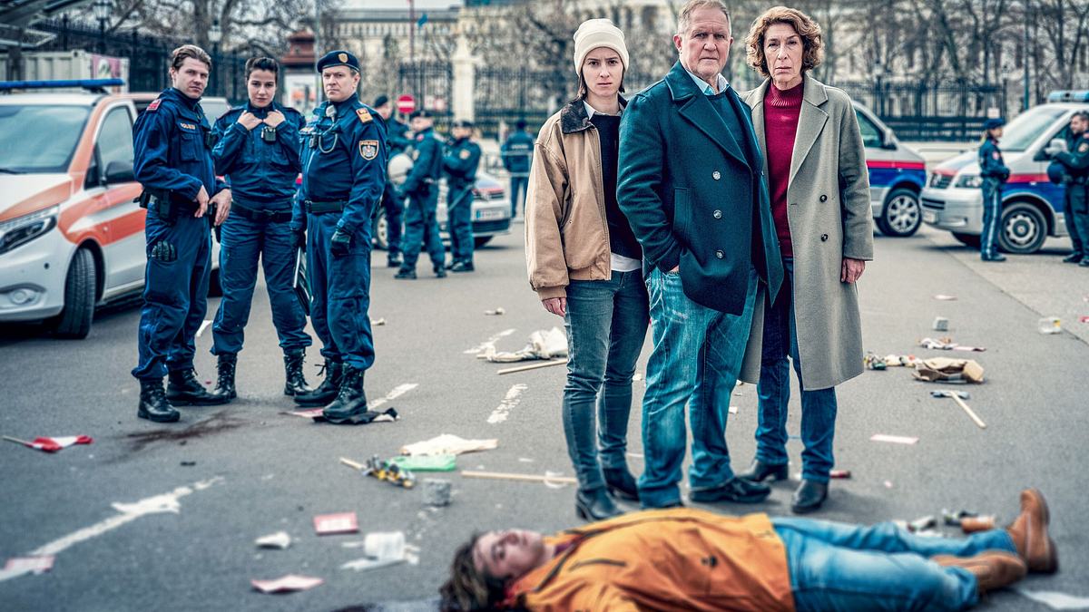 Wir sind nicht zu fassen Man sieht das Wiener-Tatort Duo Eisner und Fellner, die für ihren Fall Wir sind nicht zu fassen vor der Leiche eines jungen Mannes stehen.