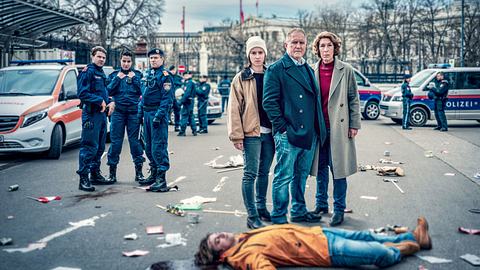 Man sieht das Wiener-Tatort Duo Eisner und Fellner, die für ihren Fall Wir sind nicht zu fassen vor der Leiche eines jungen Mannes stehen. - Foto: ORF/Landsiedl/Petro Domenigg