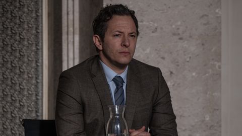Dr. Martin Roth sitzt mit konzentriertem Blick an einem Tisch. Er hat die Hände gefaltet und einen Anzug an. - Foto: © Prime Video, Britta Krehl
