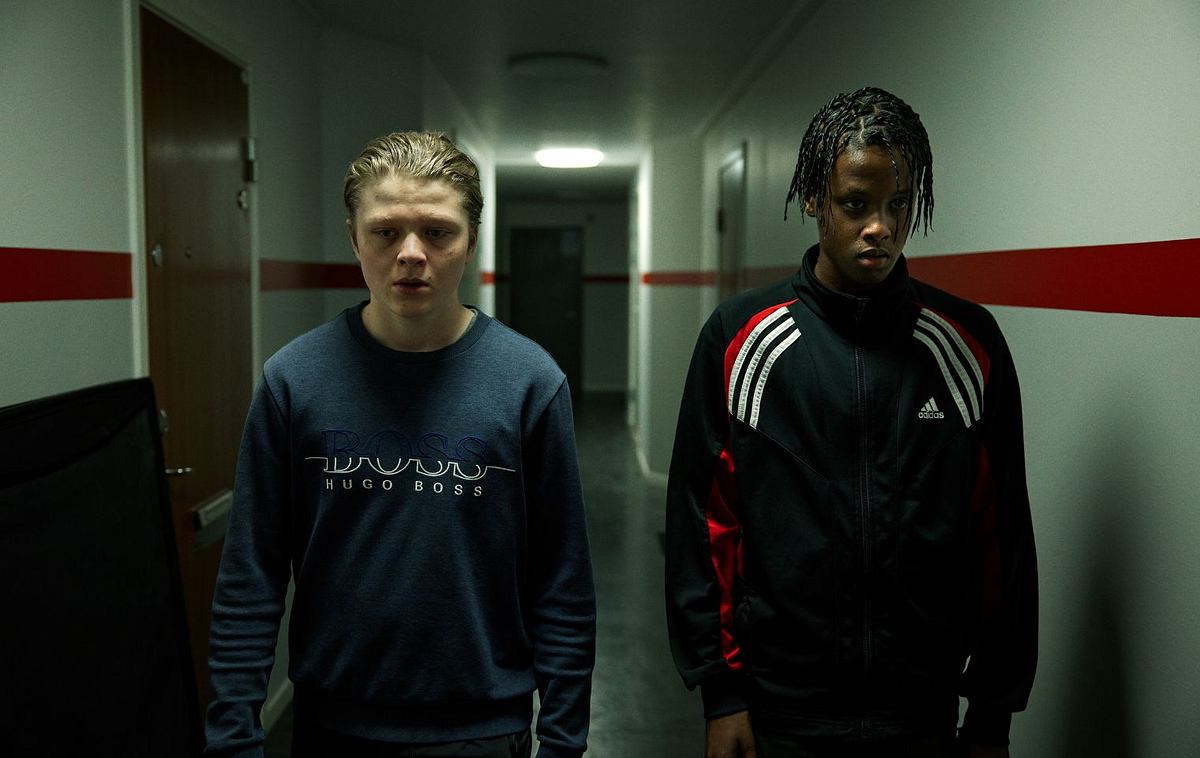 Halbtotale der Protagonisten der Serie, zwei vierzehnjährige Jungs in einem Schulflur
