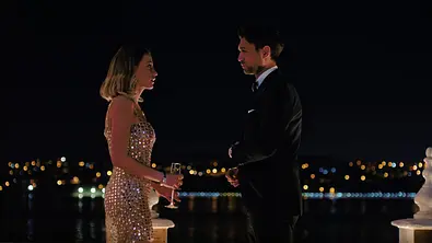 Frau im Glitzerkleid un Mann im Anzug stehen sich im Dunkeln gegenüber - Foto: © 2024 Netflix, Inc.