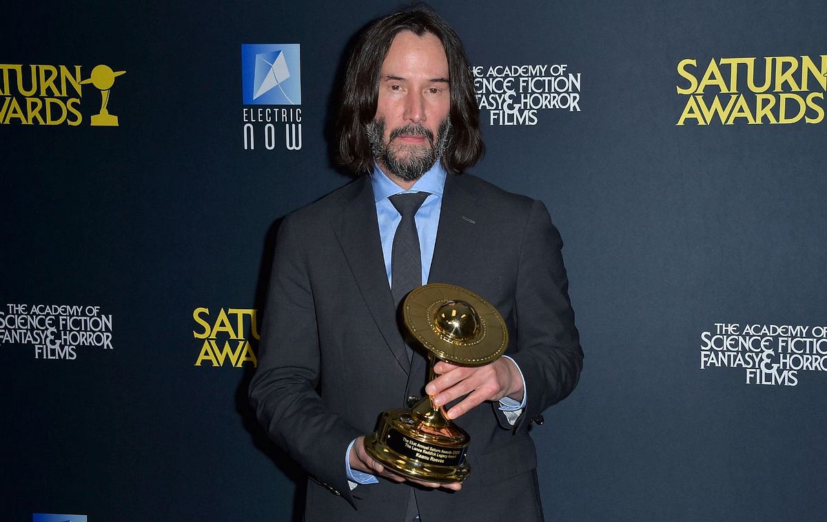 Keanu Reeves auf dem roten Teppich mit Preis in der Hand
