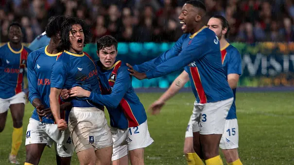 Szene auf dem Fußballfeld, Spieler freuen sich - Foto: Apple TV+