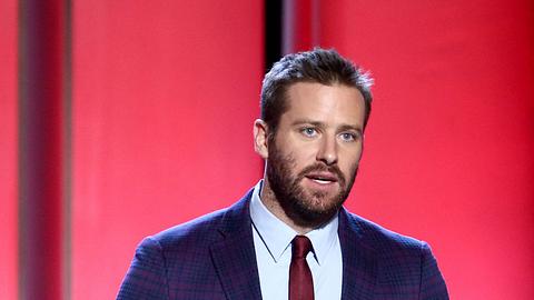 Schauspieler Armie Hammer steht im karierten Anzug auf der Bühne und spricht - Foto: Getty Images