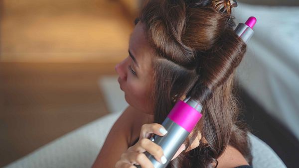 Frau frisiert sich Haare mit Dyson Airwrap - Foto: Getty Images / Enes Evren