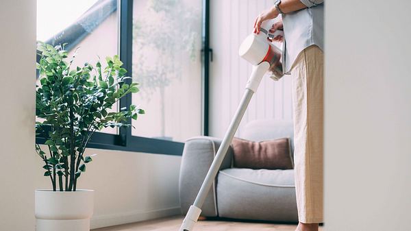 Frau saugt Staub mit einem Akku Staubsauger - Foto: FreshSplash / GettyImages