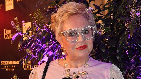 Maritta Emser posiert in weißem Kleid und Glitzerbrille - Foto: IMAGO / Spöttel Picture