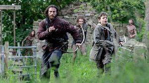 Man sieht Aaron Taylor-Johnson und Alife WIlliams, wie sie mit Pfeil und Bogen vor drei Untoten in einer Graslandschaft mit den Überresten eines Gebäudes, sowie einem Zaun weglaufen. - Foto: IMAGO / Landmark Media