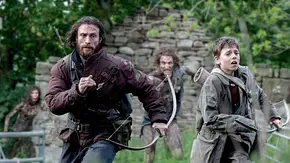 Jamie (Aaron Taylor-Johnson, links) und Spike (Alfie Williams) laufen auf einer grünen Wiese vor einer Ruine vor Infizierten weg. Sie tragen Funktionskleidung und sind mit Pfeil und Bogen bewaffnet. Die Infizierten tragen keine sonderlich auffällige Kleidung, aber schauen finster drein, während Spike und Jamie eher ernst davonlaufen. - Foto: IMAGO / Landmark Media Jamie (Aaron Taylor-Johnson, links) und Spike (Alfie Williams) laufen auf einer grünen Wiese vor einer Ruine vor Infizierten weg. Sie tragen Funktionskleidung und sind mit Pfeil und Bogen bewaffnet. Die Infizierten tragen keine sonderlich auffällige Kleidung, aber schauen finster drein, während Spike und Jamie eher ernst davonlaufen. - Foto: IMAGO / Landmark Media