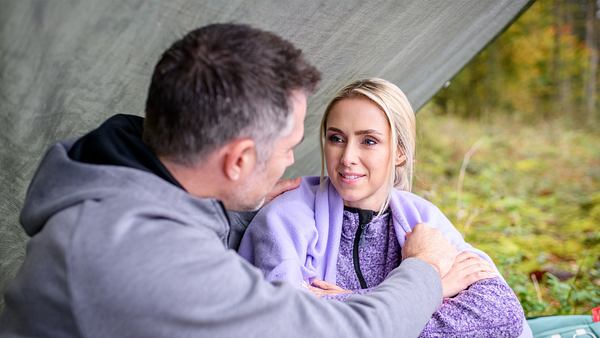 Larissa und Yannik sitzen draußen unter einer Zeltplanne. Er berührt sie an ihrer Schulter. Sie schaut ihn verliebt an. - Foto: ARD/WDR/Christof Arnold