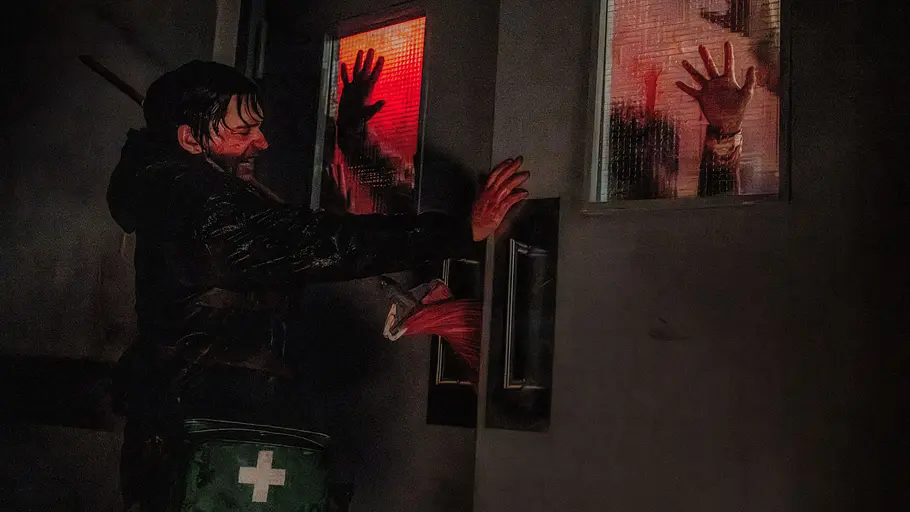 Resident Evil Austin Abrams steht für „Resident Evil“ vor einer Tür, an die mehrere Hände klopfen.