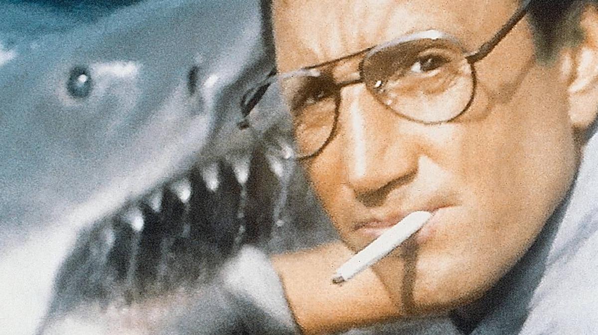 Der weiße Hai Roy Scheider als Brody in Der weiße Hai. Er hat eine Zigarette im Mund und ist kurz davor versehentlich den titelgebenden Hai zu füttern.