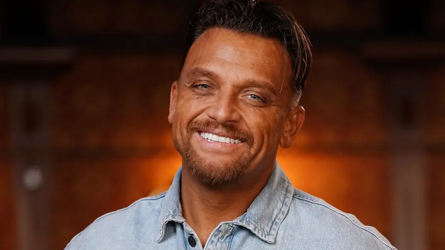 Menowin Fröhlich will DSDS dieses Mal gewinnen. Menowin Fröhlich strahlt im blauen Hemd.