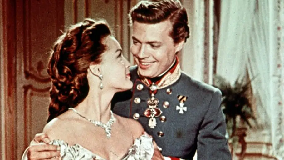 Sissi und Franz stehen hintereinander und lächeln sich an