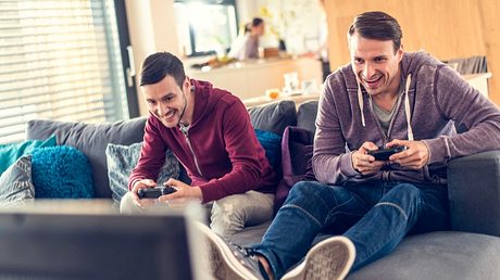 Zwei Männer spielen mit einer Konsole - Foto: iStock/simonkr