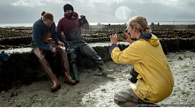Lissi (Morgane Ferru) dokumentiert die Austernzucht mit den Arbeitern Briac (Guillaume Thierry) und Jean (Liliom Lewald, li.). - Foto: RD Degeto Film/Bantry Bay Productions GmbH/Christine Tamalet Lissi (Morgane Ferru) dokumentiert die Austernzucht mit den Arbeitern Briac (Guillaume Thierry) und Jean (Liliom Lewald, li.). - Foto: RD Degeto Film/Bantry Bay Productions GmbH/Christine Tamalet