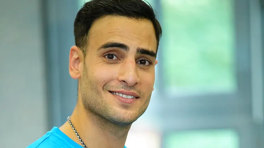 Timur Ülker im blauen Shirt lächelt in die Kamera.