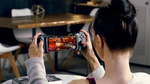 Eine rau nutzt den Handy-Controller Razer Kishi, bei dem ein Smartphone zischen zwei Controller-Hälften eingespannt wird, sodass es sich wie eine Nintendo Switch bedienen lässt. - Foto: Razer/PR