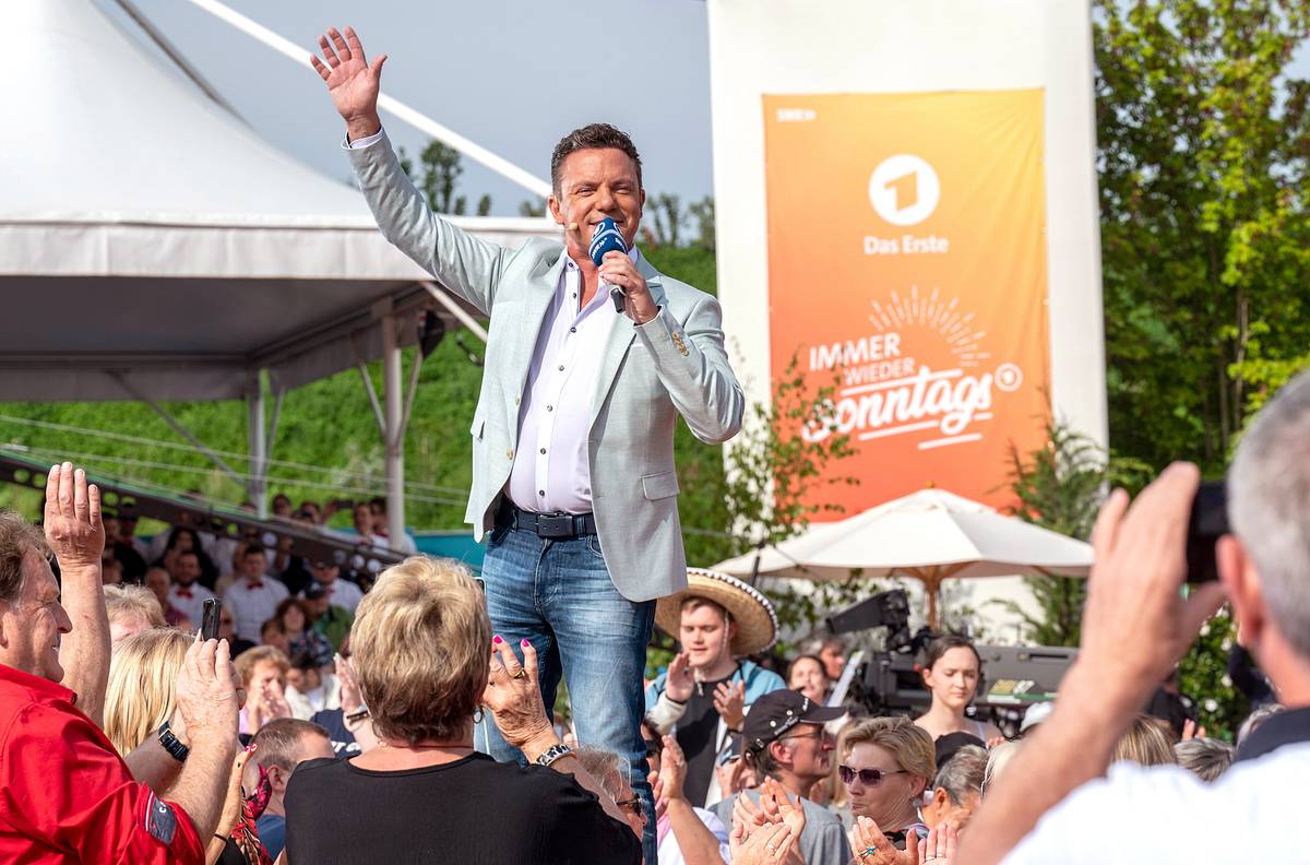 Stefan Mross steht mit Mikrofon vor dem Publikum und winkt während der ARD-Sendung „Immer wieder sonntags“ im Europa-Park Rust.