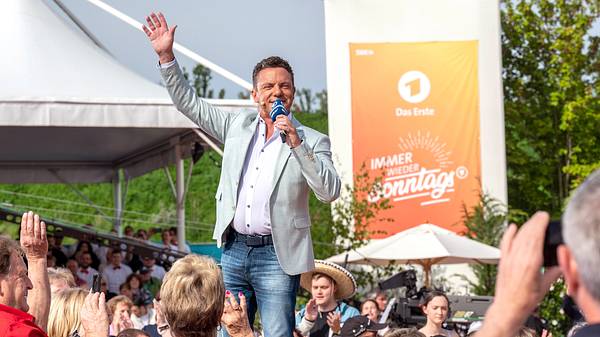 Stefan Mross steht mit Mikrofon vor dem Publikum und winkt während der ARD-Sendung „Immer wieder sonntags“ im Europa-Park Rust. - Foto: Media Press