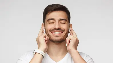 Ein Mann nutzt kabellose In-Ear-Kopfhörer. - Foto: iStock / Damir Khabirov