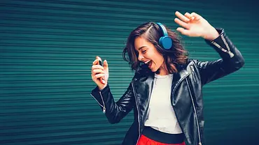 Eine Frau hört mit Bluetooth-Kopfhörern Musik. - Foto: iStock / martin-dm