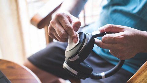 Kopfhörer, die mit einem Tuch gereinigt werden - Foto: iStock/goc