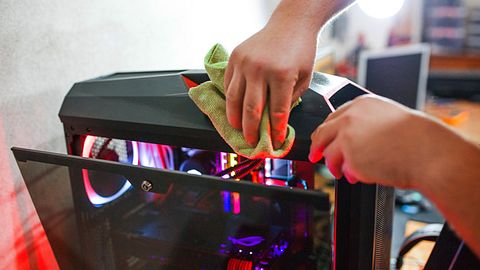 Person reinigt das Gehäuse eines PCs - Foto: iStock/Viktorcvetkovic