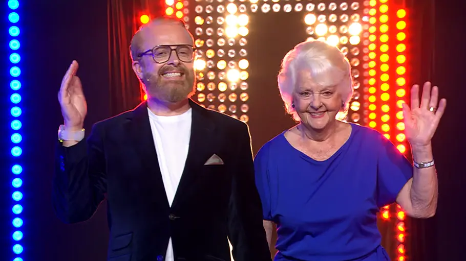Ross Antony in einem schwarzen Anzug und seine Mutter Vivien in einem blauen Kleid bei „Europa grillt den Henssler“