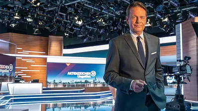 Backstage - Aktenzeichen XY... Ungelöst - Spurensuche hinter den Kulissen: Moderator Rudi Cerne steht im Studio und schaut lächelnd in die Kamera. - Foto: ZDF