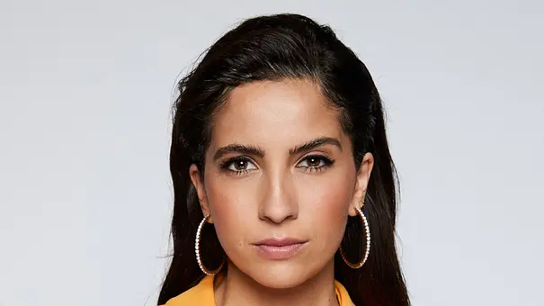 Chryssanthi Kavazi mit langen dunklen Haaren, großen Creolen und gelbem Blazer blickt vor hellgrauem Hintergrund in die Kamera. - Foto: RTL /  Bernd Jaworek 
