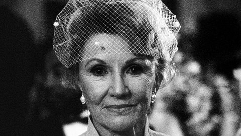 Schauspielerin Phyllis Coates 1990 auf einem Schwarz-Weiß-Foto. Sie trägt ein festliches Kostüm und eine Kopfbedeckung aus Netzstoff und fokussiert mit geradem Blick die Kamera - Foto: IMAGO / Everett Collection