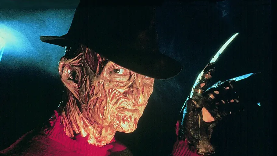 A Nightmare on Elm Street Freddy Krueger schaut recht neutral in die Kamera und hält seine Klingenhand hoch.
