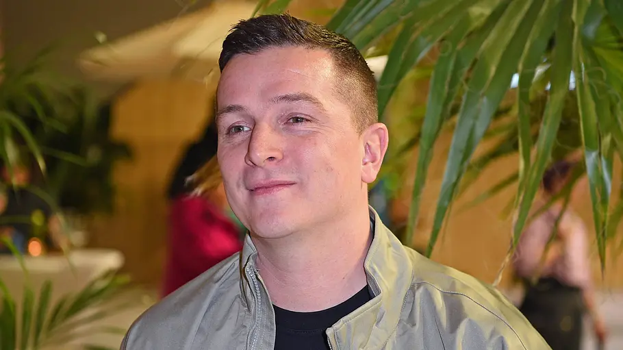 Aaron Troschke nicht bei „Promi Big Brother“ dabei. Rauswurf: Aaron Troschke, hier vor Palmenhintergrund, ist nicht länger Kioskbetreiber bei Promi Big Brother.