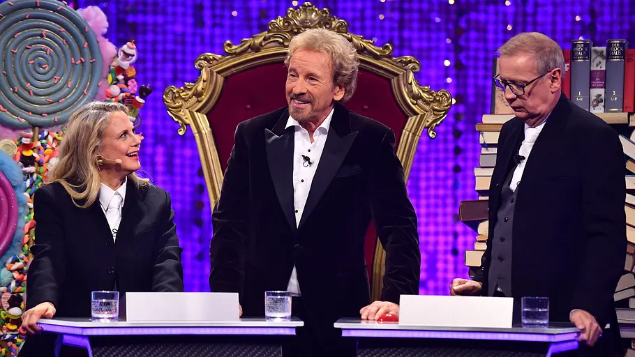 Denn sie wissen nicht, was passiert – Die Jauch-Gottschalk-Schöneberger-Show“ Von links: Barbara Schöneberger, Thomas Gottschalk, Günther Jauch bei der Denn sie wissen nicht, was passiert – Die Jauch-Gottschalk-Schöneberger-Show“. Sie tragen alle ein schwarzes Jacket, ein weißes Hemd. Im Hintergrund ist ein lilaner HIntergrund.