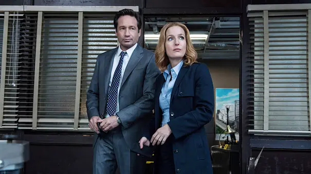Ein Foto aus alten Set-Tagen. David Duchovny steht in einem Büro neben Gillian Anderson. - Foto: IMAGO / Everett Collection