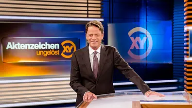 Rudi Cerne steht lächelnd im Studio von „Aktenzeichen XY“. - Foto: ZDF und Nadine Rupp Rudi Cerne steht lächelnd im Studio von „Aktenzeichen XY“. - Foto: ZDF und Nadine Rupp