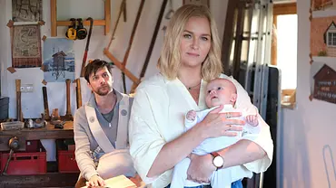 In einer Werkstatt sitzt Tom Baumgartner (Jonathan Beck) vor einer Werkbank. Im Vordergrund hält Lena Lorenz (Judith Hoersch) ein Baby im Arm und schaut in die Ferne. - Foto: © ZDF/Jacqueline Krause-Burberg In einer Werkstatt sitzt Tom Baumgartner (Jonathan Beck) vor einer Werkbank. Im Vordergrund hält Lena Lorenz (Judith Hoersch) ein Baby im Arm und schaut in die Ferne. - Foto: © ZDF/Jacqueline Krause-Burberg