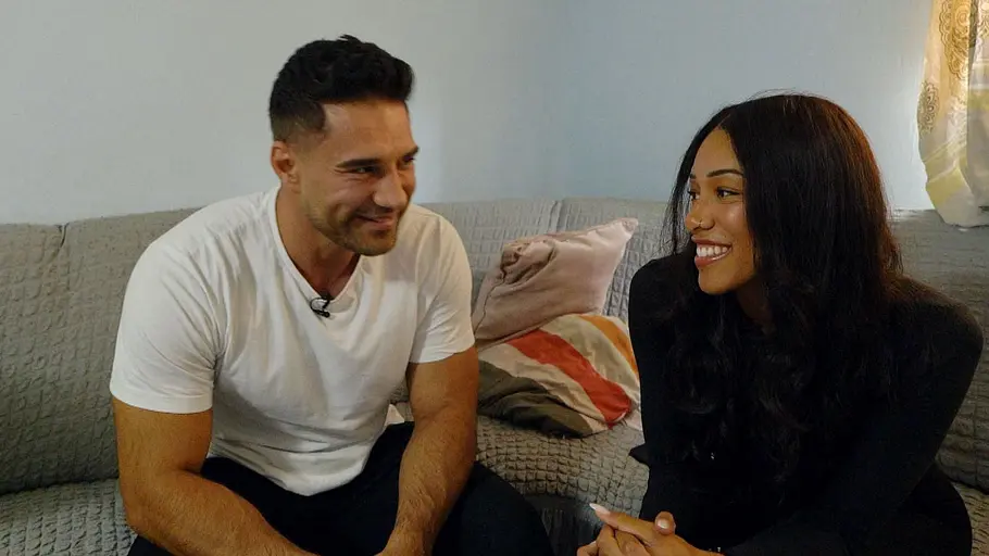 Aleks und Vanessa Aleks und Vanessa sitzen zusammen auf einer Couch und lächeln sich an.