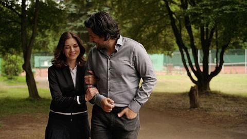 Gabriella hängt sich in Maximilians Arm bei Alles was zählt. Er schaut sie strahlend an, sie lächelt und schaut auf den Boden. - Foto: RTL