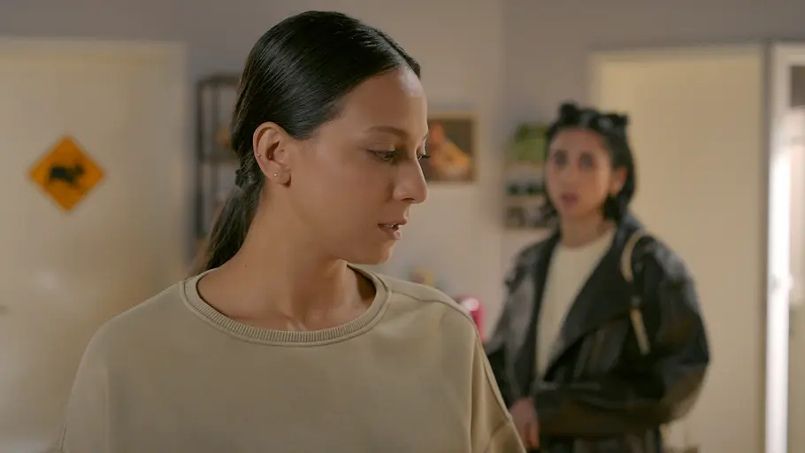 ALLES WAS ZÄHLT-Vorschau FOLGE 5068 Mittwoch 4. November Charlie im beigen Oberteil blickt nach unten. Hinter ihr steht unscharf Leyla in schwarzer Lederjacke.