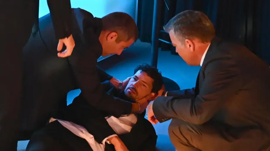 Jan liegt verwirrt auf dem Boden, Dragan und ein Kollege stehen um ihn herum und stützen ihn