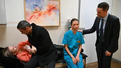 Isabelle liegt auf einer Krankenliege und wird von Dragan umsorgt. Nathalie sitzt bedrückt am Ende des Bettes und Killian packt ihr eine Hand auf die Schulter - Foto: RTL / Julia Feldhagen