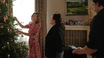 Nathalie schmückt den Weihnachtsbaum der Steinkamp und redet dabei mit Vanessa. Maximilian steht vor ihnen. - Foto: RTL / Julia Feldhagen