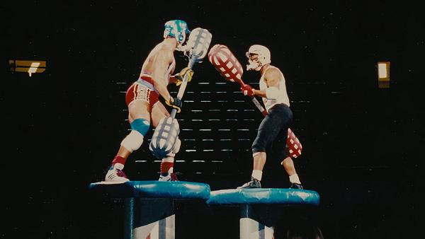 Zwei Teilnehmer der Sendung American Gladiators stehen sich auf zwei Plattformen gegenüber und haben lange Kampfstäbe in ihren Händen. - Foto: TMDB