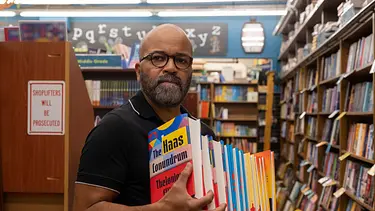 Thelonious „Monk“ Ellison (Jeffrey Wright) steht mit Brille und einem Stapel bunter Bücher zwischen Bücherregalen. - Foto: © WDR/2023 MRC II Distribution Company L.P. All Rights Reserved Thelonious „Monk“ Ellison (Jeffrey Wright) steht mit Brille und einem Stapel bunter Bücher zwischen Bücherregalen. - Foto: © WDR/2023 MRC II Distribution Company L.P. All Rights Reserved