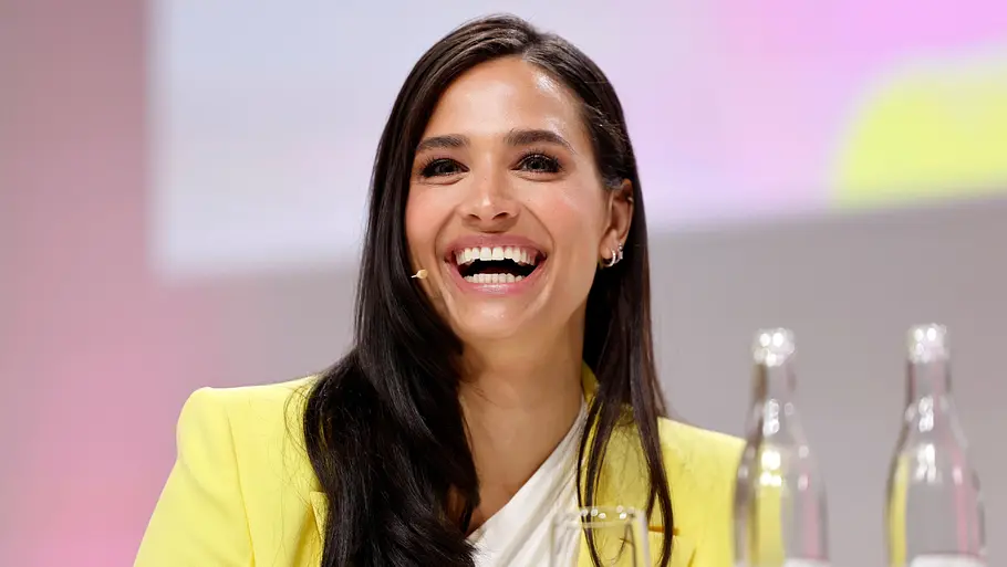 Amira Aly lacht Amira Aly sitzt an einem Pult und lacht