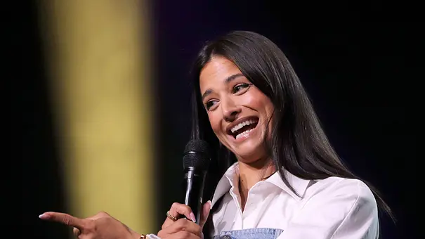 Amira Aly lacht verlegen und zeigt mit dem Finger zur Seite.  - Foto: IMAGO / Future Image