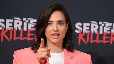 Amira Aly trägt ein weißes Shirt und einen lachsfarbenen Blazer. Sie erhebt mahnend den Finger. - Foto: IMAGO / Horst Galuschka
